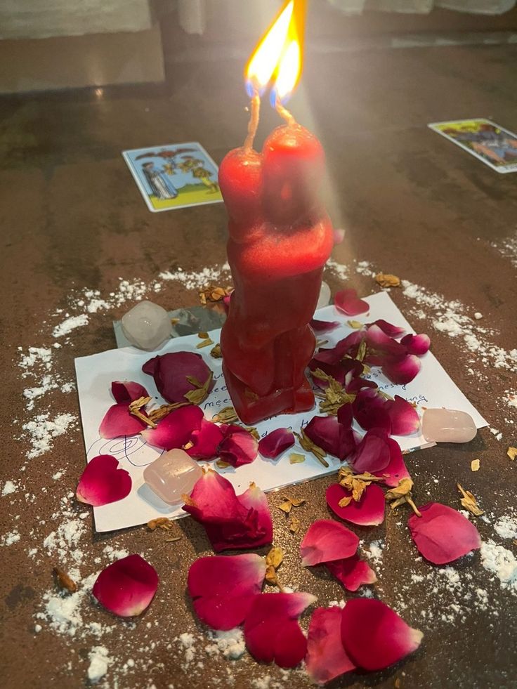 Vela roja de pareja encendida entre pétalos de rosa
